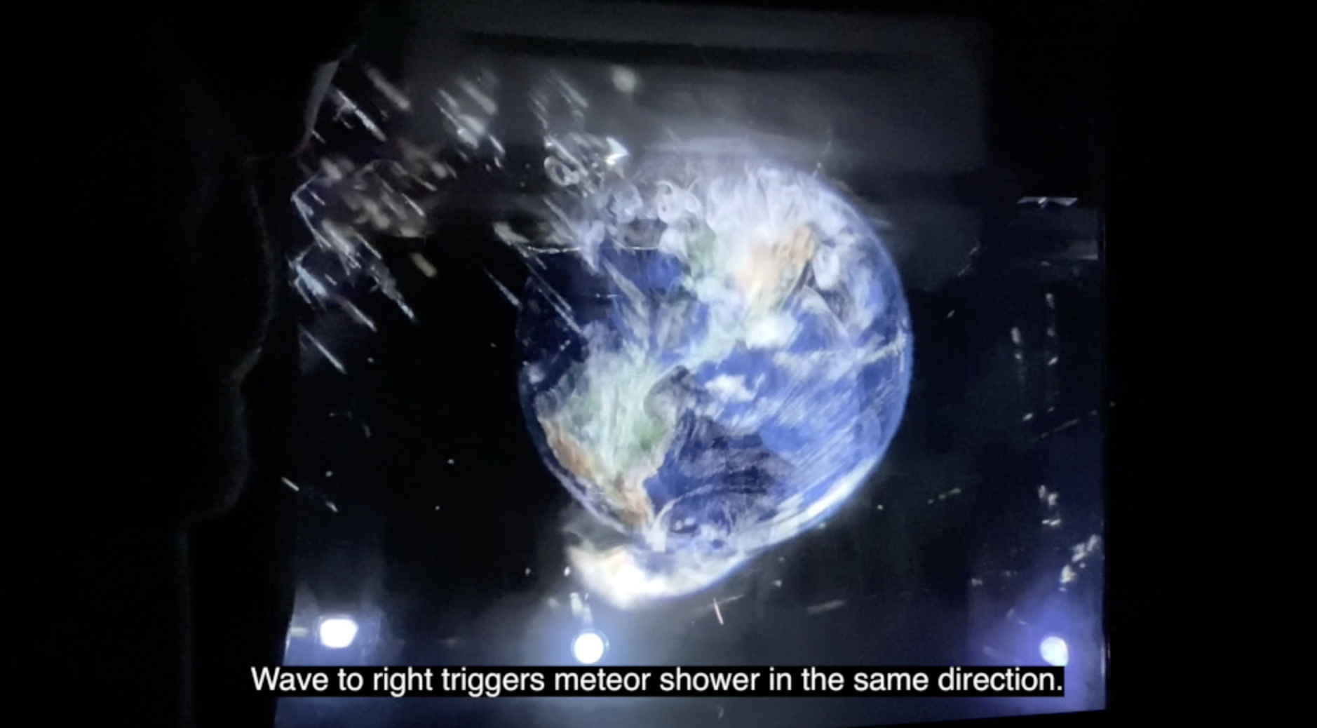 An interactive installation featuring a floating globe. As a person waves their hand, a meteor shower is triggered.